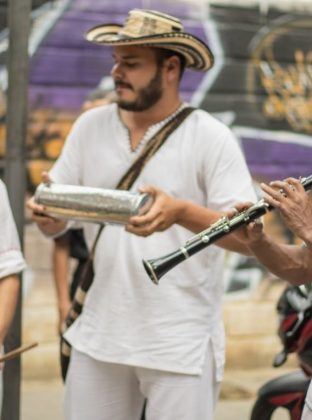 Parranda – Tres músicos interpretan con sus instrumentos  “Yo me llamo cumbia” de Toto la Momposina. Algunos extranjeros, posiblemente gringos, se divierten bailando mientras son grabados con dispositivos móviles.